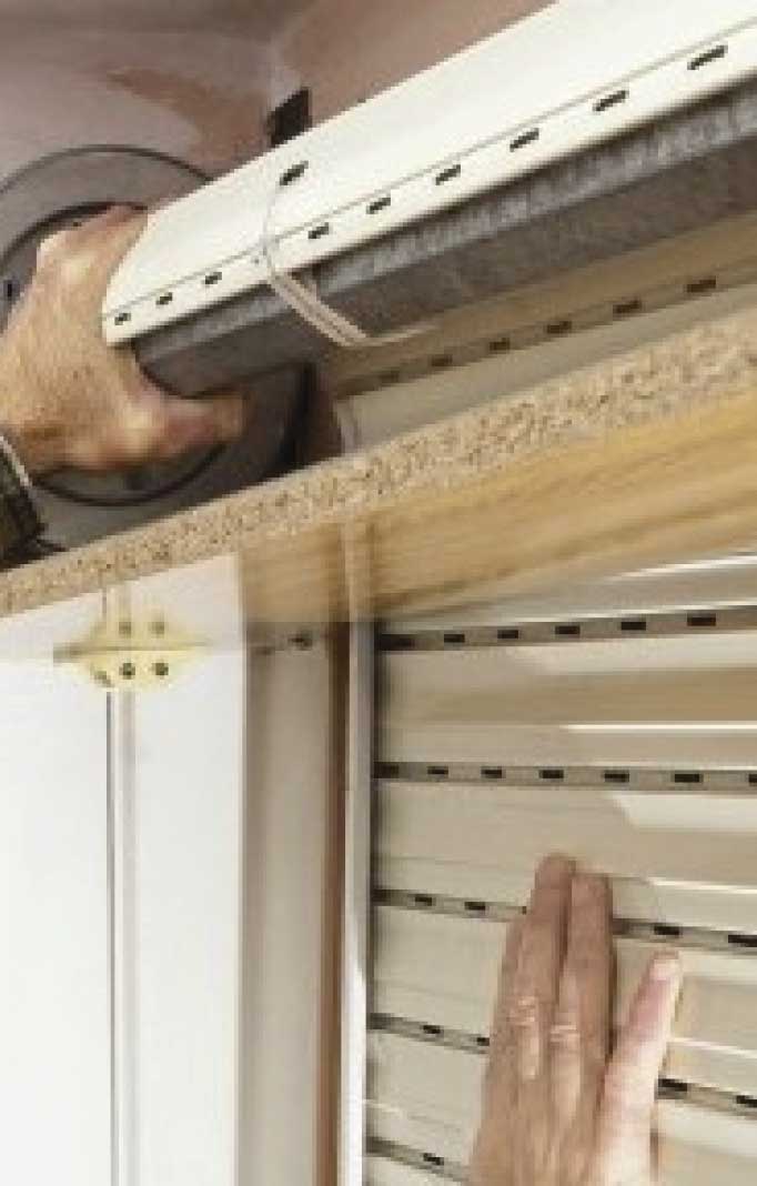 Manos reparando una persiana con herramientas especializadas